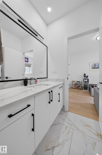 Dual sink vanity with white cabinetry, matte black hardware, and a stone-finish countertop - 17128 2 Street Nw, Edmonton, AB 