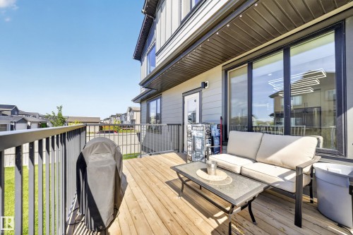 Outdoor deck featuring wood-finish flooring, black metal railings with steps down to the spacious yard. - 17128 2 Street Nw, Edmonton, AB 