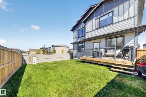 Expansive grass yard with wood fencing and a raised wood deck featuring metal railings - 17128 2 Street Nw, Edmonton, AB 
