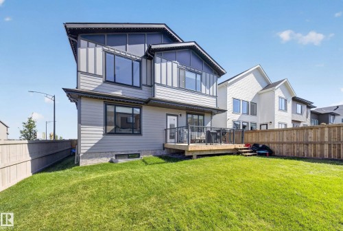 Expansive green lawn, wood deck with black metal railings, and a privacy fence - 17128 2 Street Nw, Edmonton, AB 