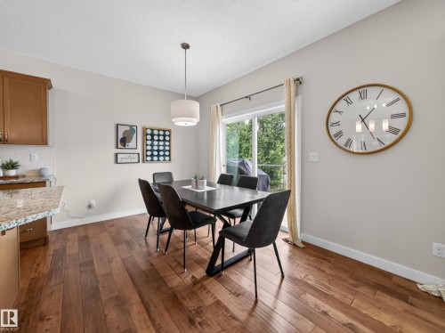 Dining area featuring wood-finish flooring, a contemporary pendant light fixture, and a sliding glass door - 6504 48 Avenue, Beaumont, AB - Indoor Photo Showing Dining Room