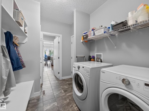 Dedicated laundry area featuring a washer and dryer set, wire shelving for storage, and a tiled floor - 6504 48 Avenue, Beaumont, AB - Indoor Photo Showing Laundry Room