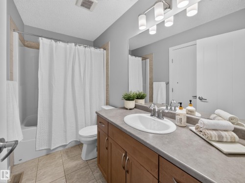 Full vanity with an integrated sink, laminate countertop, and wood-finish cabinetry - 6504 48 Avenue, Beaumont, AB - Indoor Photo Showing Bathroom