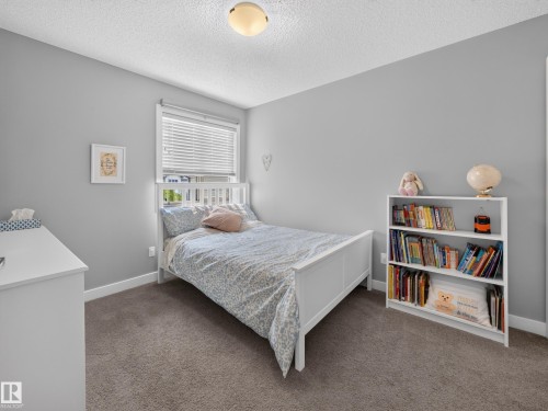 Carpeted room with a ceiling-mounted light fixture, a window featuring horizontal blinds, and light gray painted walls - 6504 48 Avenue, Beaumont, AB - Indoor Photo Showing Bedroom