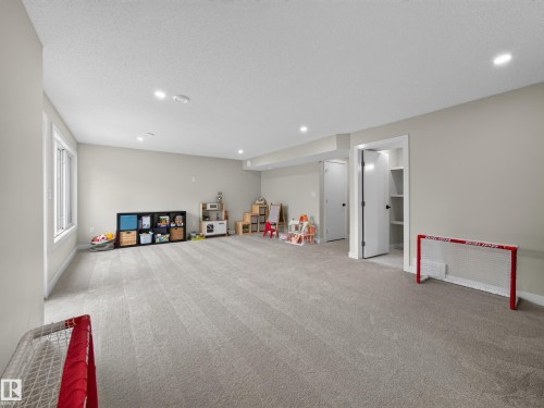Spacious carpeted room featuring recessed lighting, a large window, and light-toned walls - 6504 48 Avenue, Beaumont, AB - Indoor Photo Showing Other Room