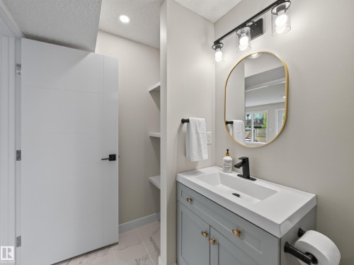 Bathroom vanity featuring a light gray cabinet with gold-finish hardware, a white integrated sink, and a matte black single-handle faucet - 6504 48 Avenue, Beaumont, AB - Indoor Photo Showing Bathroom