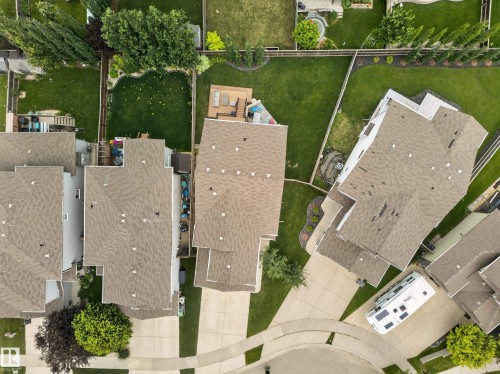 Residential property featuring a brown shingle roof, concrete driveway, and a fenced backyard with a green lawn - 6504 48 Avenue, Beaumont, AB - 