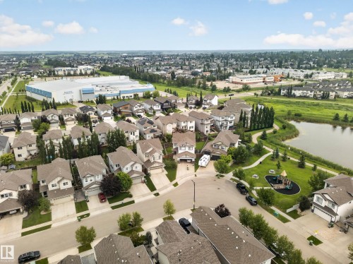 Aerial perspective showcasing a residential neighborhood with detached homes, green spaces, and a nearby body of water - 6504 48 Avenue, Beaumont, AB - Outdoor With View