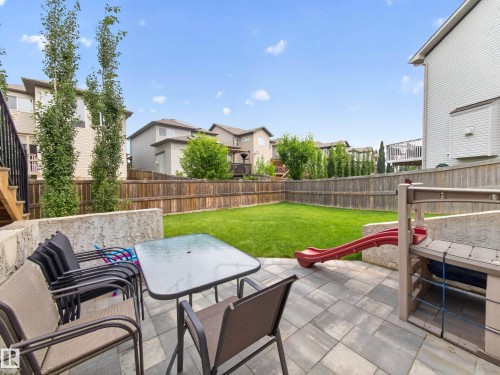 Expansive backyard featuring a large paved patio, manicured lawn, and natural wood fencing - 6504 48 Avenue, Beaumont, AB - Outdoor With Deck Patio Veranda