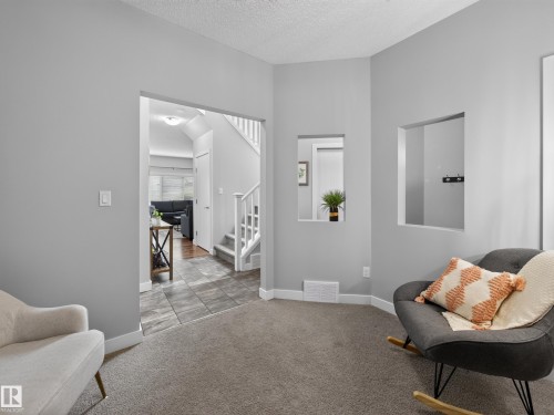 Carpeted room featuring integrated wall cut-outs and an arched entryway - 6504 48 Avenue, Beaumont, AB - Indoor