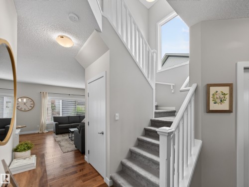Two-story entry featuring white painted banisters, grey carpeted stairs, and a large upper-level window - 6504 48 Avenue, Beaumont, AB - Indoor Photo Showing Other Room