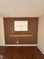 Feature wall with vertical wood slat detailing, an integrated floating wood shelf, and a ceiling-mounted baseboard heater - 