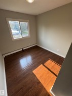 Room featuring dark wood-finish flooring, light neutral-toned walls, and a white baseboard trim - 