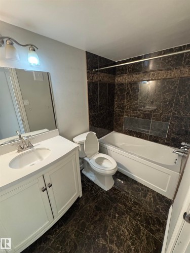 Bathroom featuring dark marbled tile flooring and bathtub surround - #205 10140 151 St Nw, Edmonton, AB - Indoor Photo Showing Bathroom