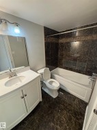 Bathroom featuring dark marbled tile flooring and bathtub surround - 