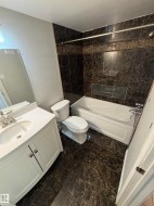 Contemporary full bathroom featuring a white vanity with integrated sink, chrome faucet, and a large wall mirror - 