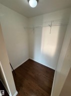Compact storage space featuring wood-finish flooring, white walls, white baseboards, and a single wire shelving unit - 