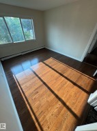 Room featuring wood-finish flooring, a baseboard heating unit, and white trim - 