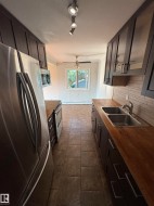 Galley kitchen featuring dark wood-finish cabinetry, stainless steel appliances, and wood-finish countertops - 