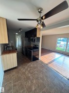 Kitchen area featuring tiled flooring, wood-finish countertops, stainless steel appliances, and a ceiling fan with integrated lighting - 