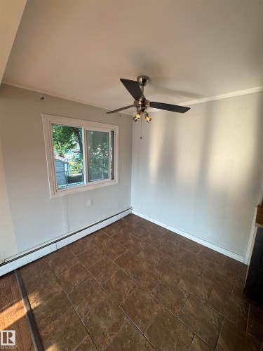 Tiled flooring with a white trim baseboard, a window, and a ceiling fan with integrated lighting - #205 10140 151 St Nw, Edmonton, AB - Indoor Photo Showing Other Room