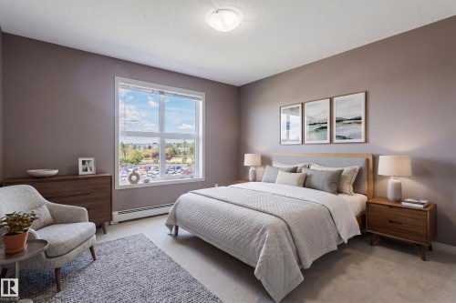 Bright bedroom with a large window, soft neutral wall color, recessed lighting, and carpeted flooring - #1-405 4245 139 Av Nw, Edmonton, AB 