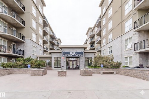 Contemporary building facade featuring a prominent entrance, stone accents, and multiple balconies - #1-405 4245 139 Av Nw, Edmonton, AB 
