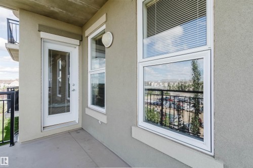 Private balcony with concrete flooring, stucco exterior, and white-framed windows - #1-405 4245 139 Av Nw, Edmonton, AB 