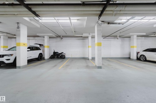 Underground parking garage with concrete flooring, overhead lighting, and clearly delineated parking spaces - #1-405 4245 139 Av Nw, Edmonton, AB 