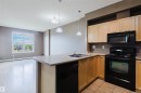 Kitchen island with a double basin stainless steel sink, black dishwasher, and pendant lighting - #1-405 4245 139 Av Nw, Edmonton, AB 