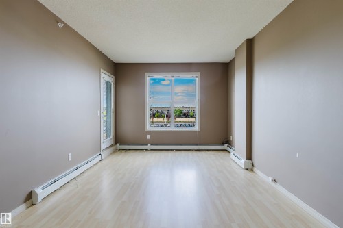Light wood-finish flooring, neutral wall tones, and a balcony access door - #1-405 4245 139 Av Nw, Edmonton, AB 