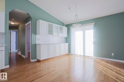 Hardwood flooring, built-in white cabinetry, glass-front upper cabinets, patterned tile backsplash, and a sliding glass door - 