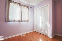 Wood-finish flooring with white trim, featuring a bifold closet door with gold-tone hardware - 
