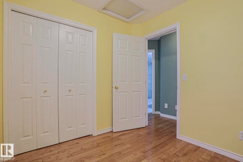 Wood-finish flooring, paneled bifold closet doors, and a paneled interior door - 15031 135 Street Nw, Edmonton, AB 