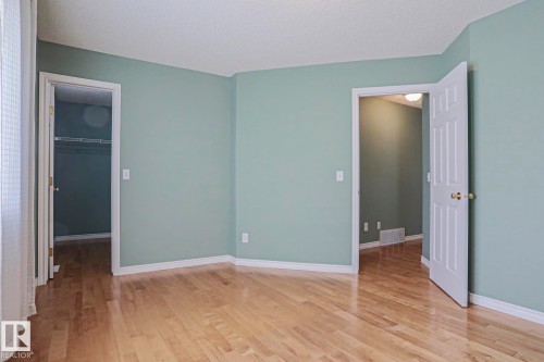 Wood-finish flooring with light-toned walls, white trim, and a paneled door - 15031 135 Street Nw, Edmonton, AB 