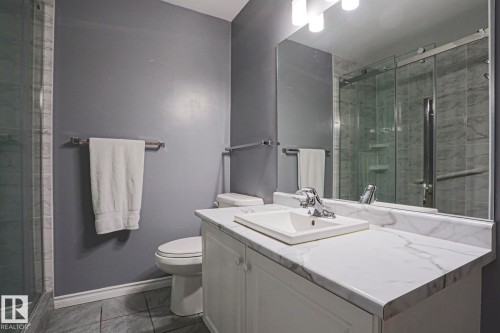 Modern bathroom featuring a white vanity with a rectangular sink, white quartz countertop, polished chrome fixtures, and ample storage - 15031 135 Street Nw, Edmonton, AB 