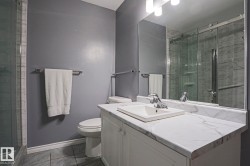 Modern bathroom featuring a white vanity with a rectangular sink, white quartz countertop, polished chrome fixtures, and ample storage - 