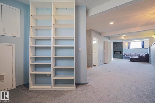 Built-in shelving units, recessed ceiling lighting, a built-in electric fireplace with a stone surround, and carpet flooring - 15031 135 Street Nw, Edmonton, AB 