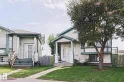 Bi Level property featuring light-colored siding with dark trim, a covered front entryway, and an established front yard tree - 