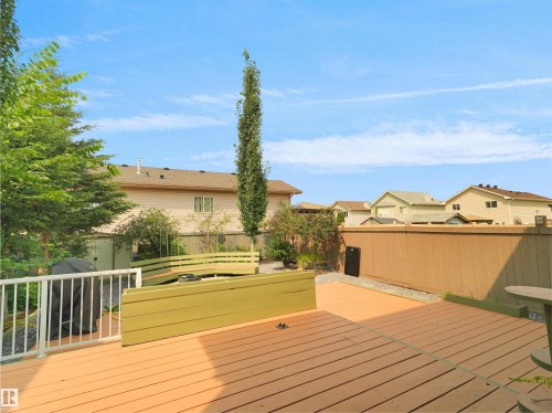 Large wood-finish deck with white railing, built-in planters, and privacy fencing - 2410 32B Street Nw, Edmonton, AB 