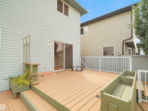 Wood-finish deck with white railing, featuring siding exterior and sliding glass door access - 2410 32B Street Nw, Edmonton, AB 