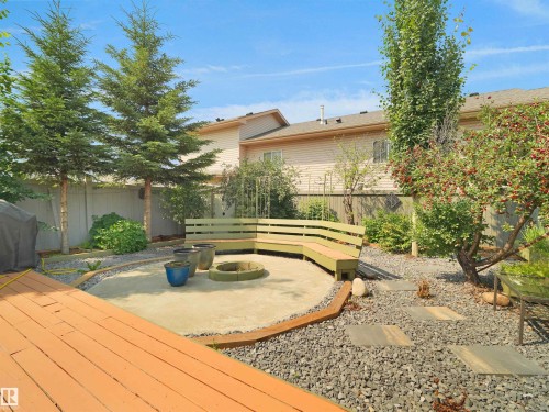 Expansive backyard featuring a concrete patio, built-in curved bench seating, and wood decking - 2410 32B Street Nw, Edmonton, AB 