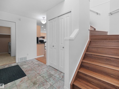 Tiled entry flooring, wood-finish staircase, white interior doors, and a ceiling-mounted light fixture - 2410 32B Street Nw, Edmonton, AB 