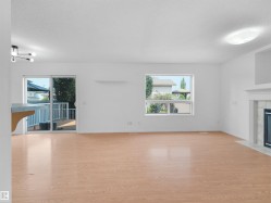 Wood-finish flooring, sliding glass door to exterior deck, and a built-in fireplace with a stone surround and mantel - 