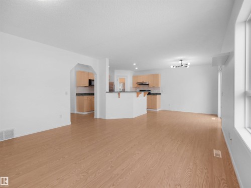 Open-concept living space featuring wood-finish flooring, recessed lighting, and a modern chandelier - 2410 32B Street Nw, Edmonton, AB 