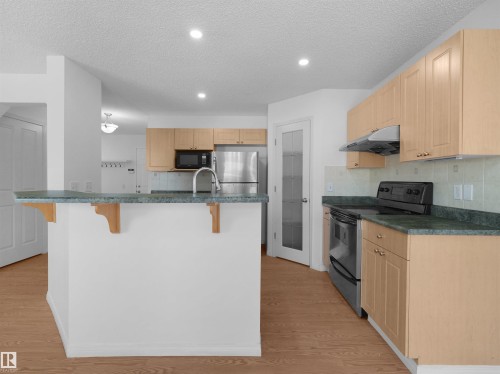 Kitchen featuring wood-finish flooring, recessed lighting, wood cabinetry, and a built-in oven - 2410 32B Street Nw, Edmonton, AB 