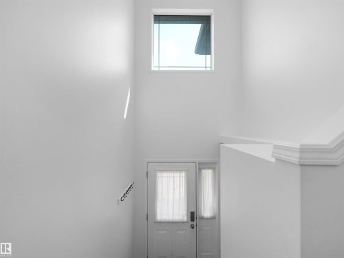 Entryway featuring a white door with a sheer curtain, a sidelight, and a transom window - 2410 32B Street Nw, Edmonton, AB 