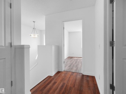 Wood-finish flooring, white walls, white trim, white doors, and a suspended ceiling light fixture - 2410 32B Street Nw, Edmonton, AB 