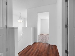 Wood-finish flooring, white walls, white trim, white doors, and a suspended ceiling light fixture - 