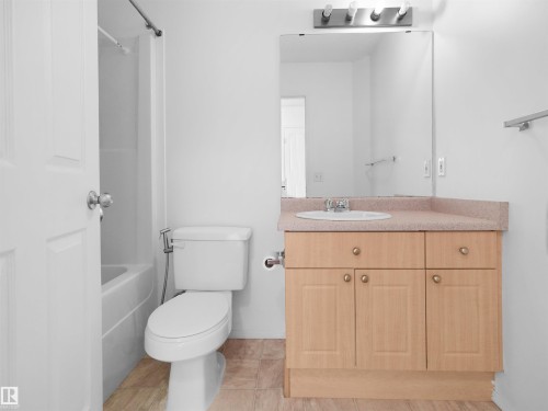 Bathroom featuring a vanity with an integrated sink, a rectangular mirror, a three-light vanity fixture, and a shower-over-tub combination - 2410 32B Street Nw, Edmonton, AB 